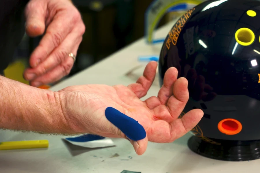 Homme utilisant du ruban adhésif pour le pouce à côté d'une boule de bowling