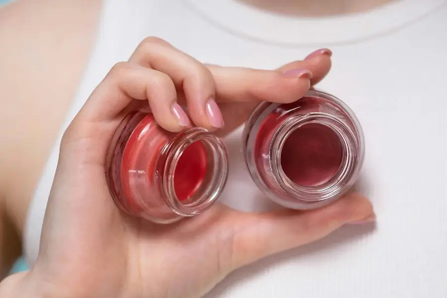 Person Holding Clear Glass Bottles Of Makeup Products by Ron Lach