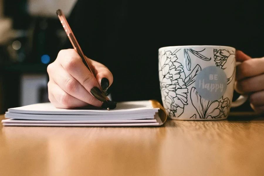 Personne tenant une tasse peinte en céramique blanche « Be Happy »