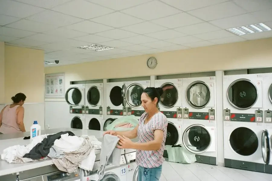 Photo of Woman Standing Inside the Laundromat by Darya Sannikova