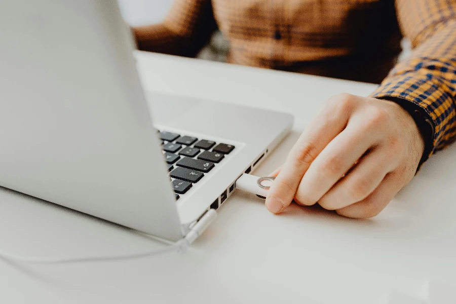 Photo of a Persons Hand Plugging in a Flash Drive into a Laptop