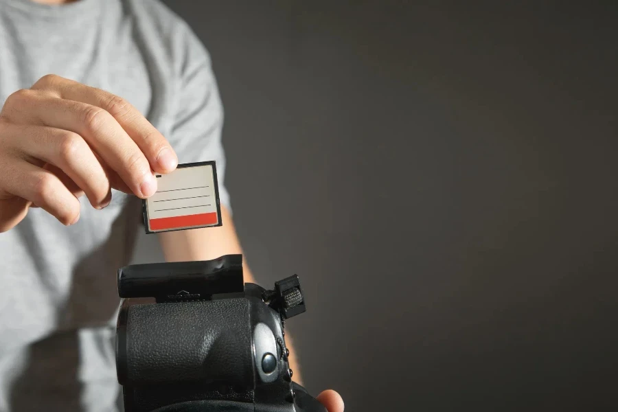 Photographe tenant une carte mémoire insérée dans un appareil photo reflex numérique