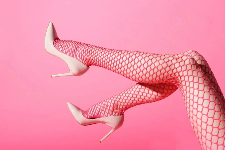 Slender female legs raised in sexy pink fishnets