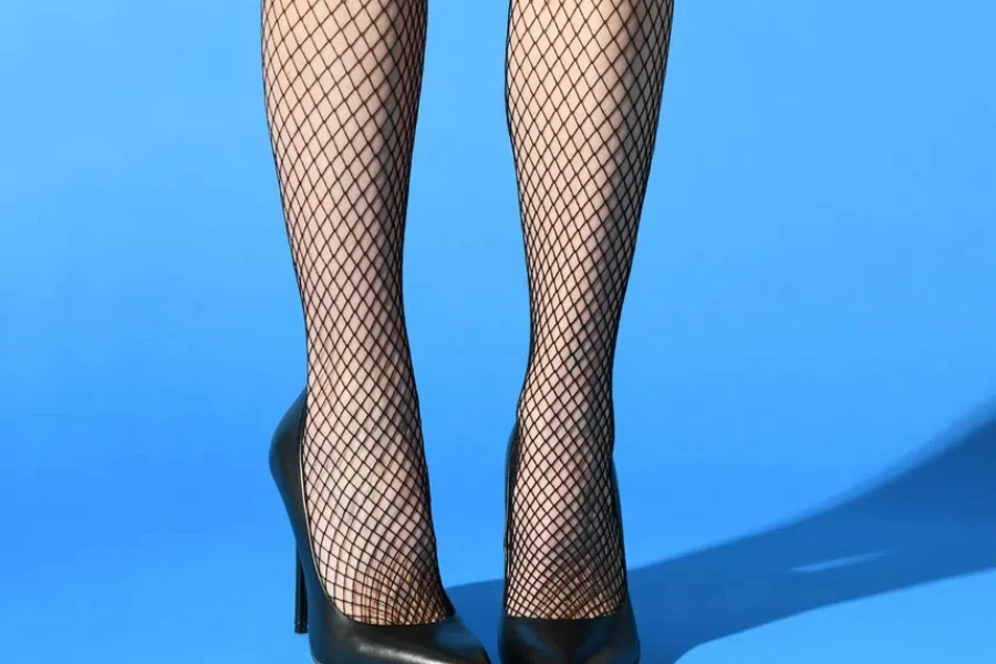 Slender sexual legs of crop unrecognizable female in fishnets