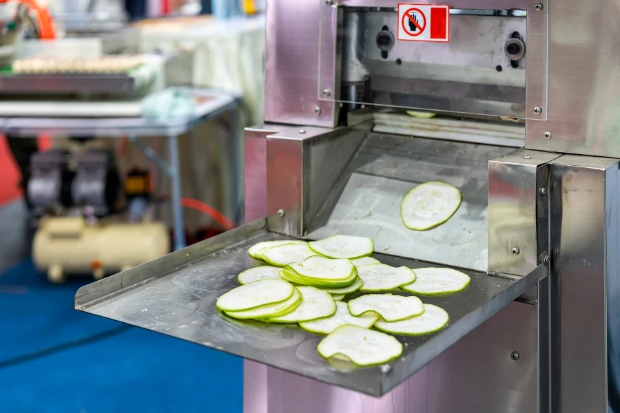 Sliced Cucumber slices on support plate after process chopping by automatic commercial vegetable slicer machine for food industrial