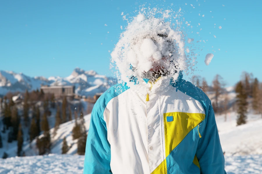Homem sorridente em férias ativas nos pitorescos Alpes Eslovenos é pego em uma briga de neve
