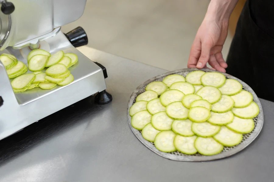 The chef in the restaurant kitchen prepares zucchini slices with a slicer