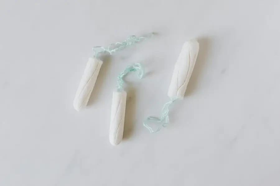 Top view of three hygienic cotton tampons placed on white marble patterned surface by Karolina Kaboompics