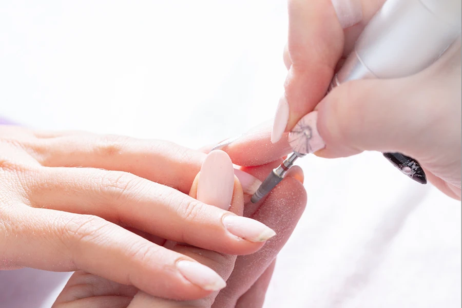 Behandlung des Nagels an der Hand mit einem speziellen Gerät mit einem Fräser für die Maniküre