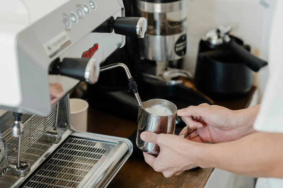 female bartender preparing milk foam for cappuccino or latte