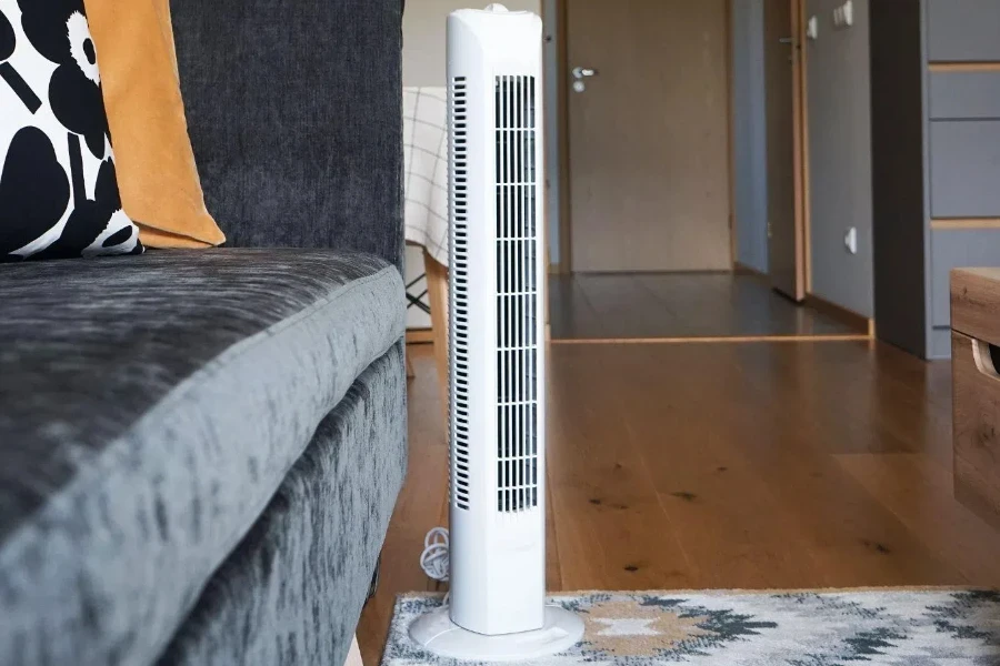 Weißer Turmventilator neben grauem Sofa