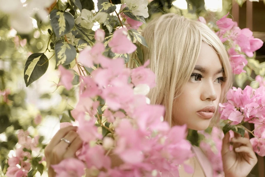 Mujer con peluca rubia sosteniendo flores rosas