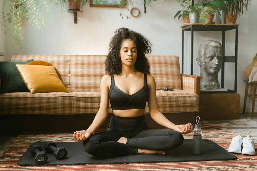 Frau in schwarzer Sportbekleidung meditiert drinnen