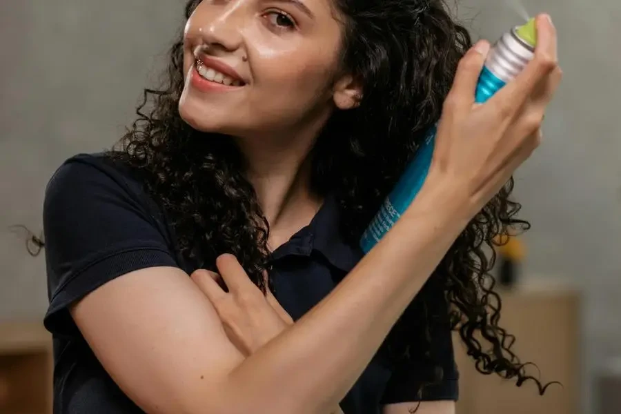 Woman in Black Shirt Spraying Hair Spray by Alena Darmel