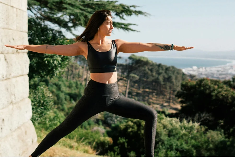 Frau im schwarzen Sport-BH und schwarzen Leggings beim Yoga