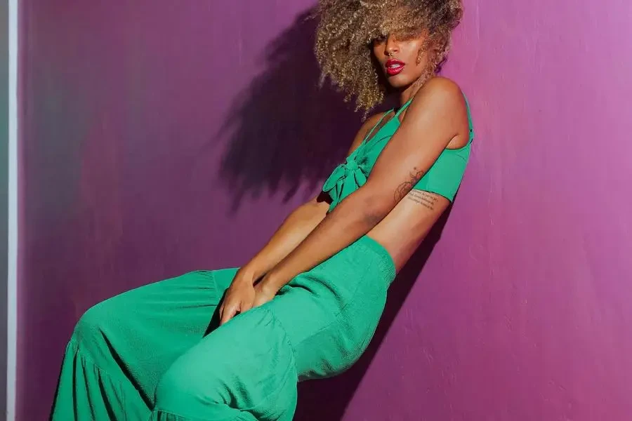 Mujer con traje verde posando sobre una pared morada de fondo, por Israel Humberto