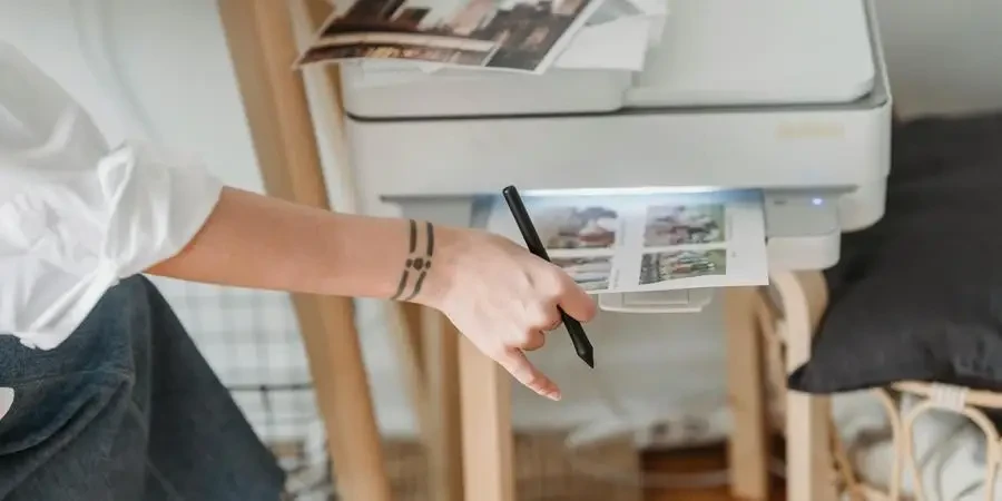 Vrouw drukt foto's af op papier terwijl ze thuis aan het vorken is door George Milton