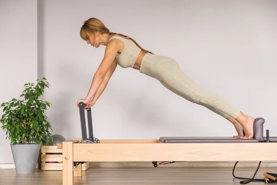 Mujer entrenando pilates en la cama reformadora