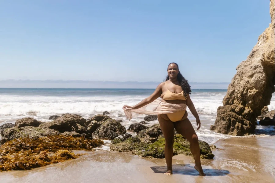 Uma mulher plus size de biquíni em pé à beira-mar