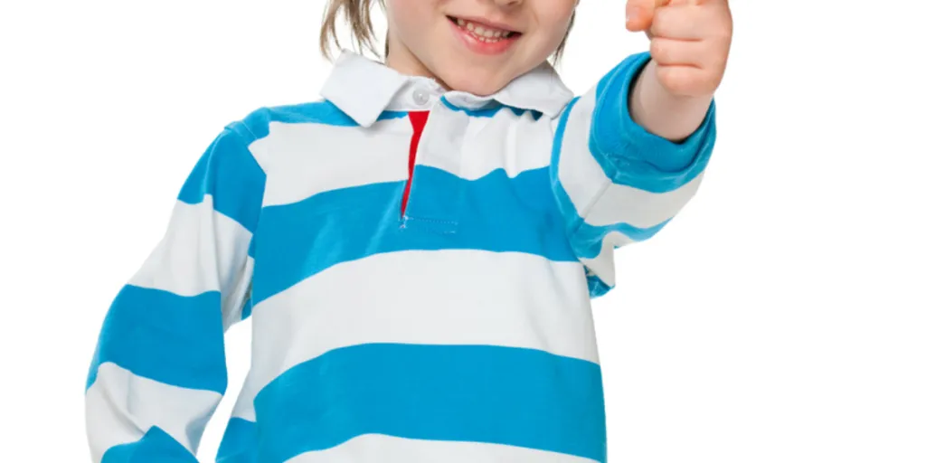Seorang anak laki-laki tersenyum mengenakan kemeja rugby biru dan putih