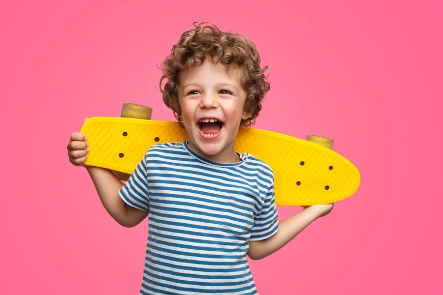 curly boy laughing and holding skateboard