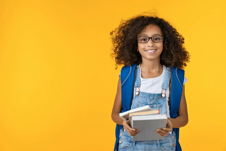 anak perempuan berkacamata memegang buku catatan dan buku