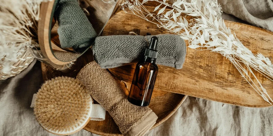 Flasche mit Pipette und gerollten Gesichtstüchern auf einem Holztablett