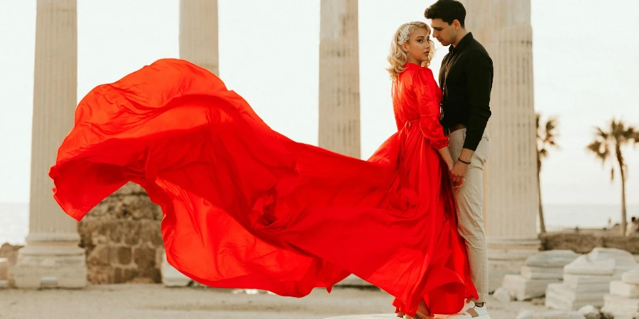 Um homem de mãos dadas com uma mulher de vestido vermelho