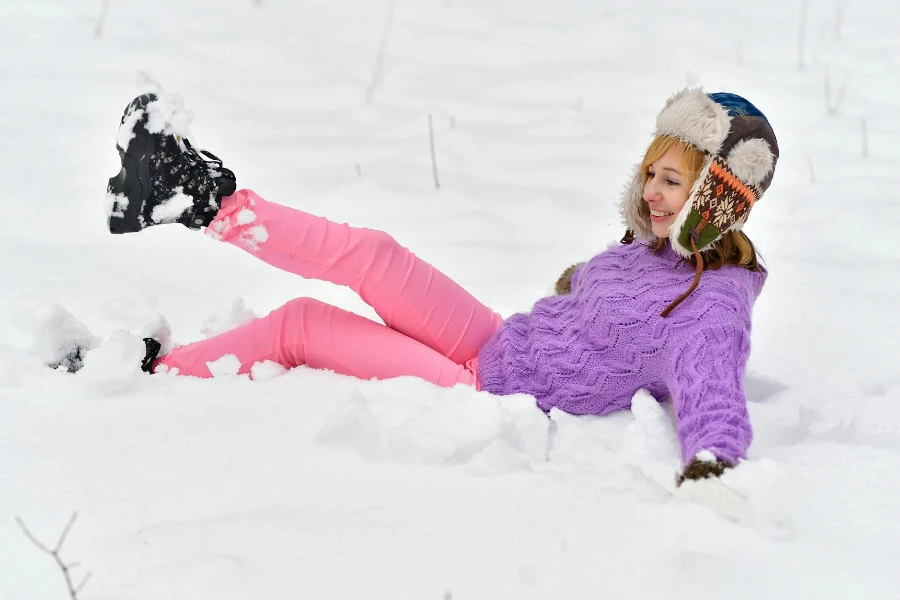 Frau im lila Pullover liegt auf Schnee
