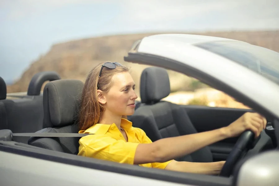 Mujer con camisa amarilla conduciendo un coche plateado