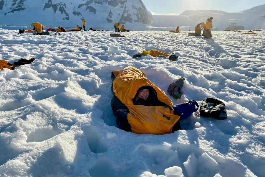 Mulher deitada em um saco de dormir na neve