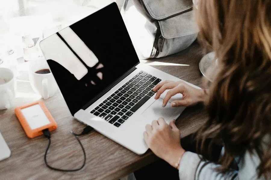 Woman Sitting Beside Table While Using Macbook