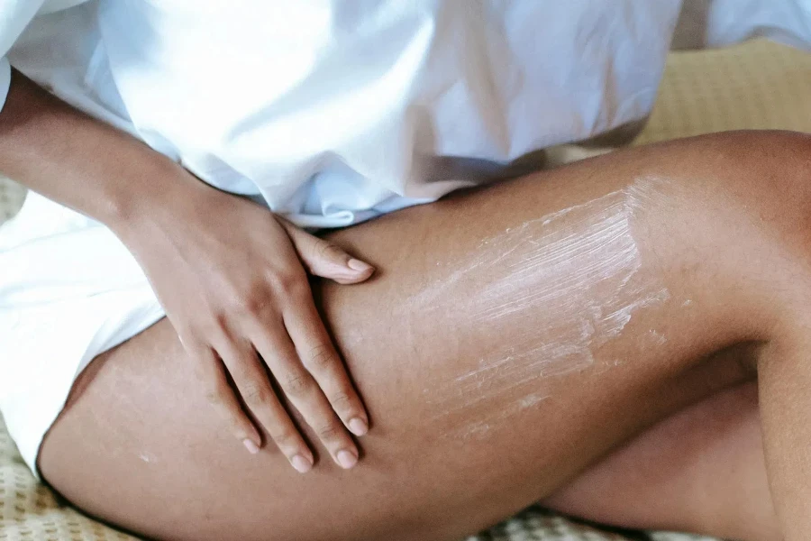 Wanita memijat kaki dengan lotion di kamar tidur