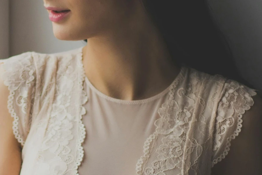 امرأة ترتدي قميصًا بأكمام قصيرة وياقة دائرية من الدانتيل الأبيض