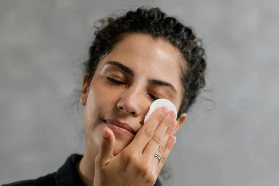 Femme en polo noir tenant un coton sur son visage