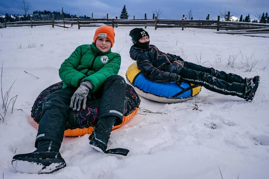 Glückliche Jungs in Oberbekleidung auf Schläuchen im Schnee