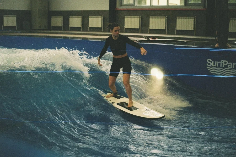 Femme en rashguard noir sur une planche de surf