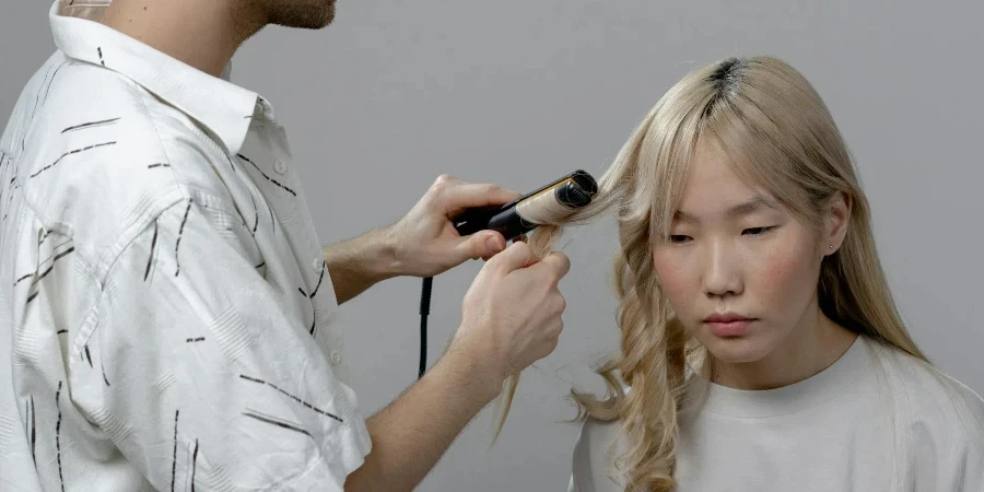 Foto eines Mannes, der einer Frau mit einem Lockenstab die Haare wäscht