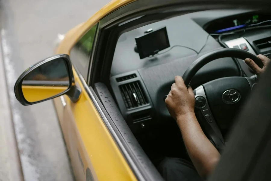 Persona sin rostro conduciendo un taxi contemporáneo en la ciudad