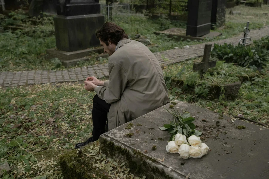 Um homem sentado perto de um túmulo