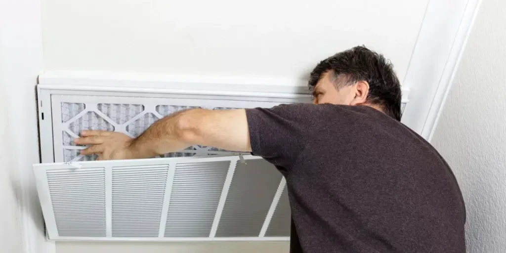 homme remplaçant un filtre sur un système de climatisation domestique