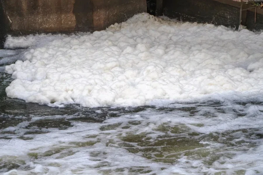 pollution of river, close up white foam floating on river