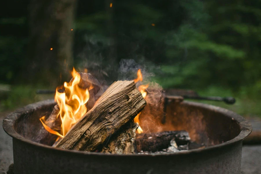 Eine Feuerstelle aus Metall mit einem darin brennenden Feuer, das Flammen und Rauch ausstößt