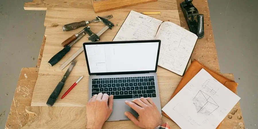 A Person Using a Laptop While on the Carpentry Workbench by Ivan Samkov