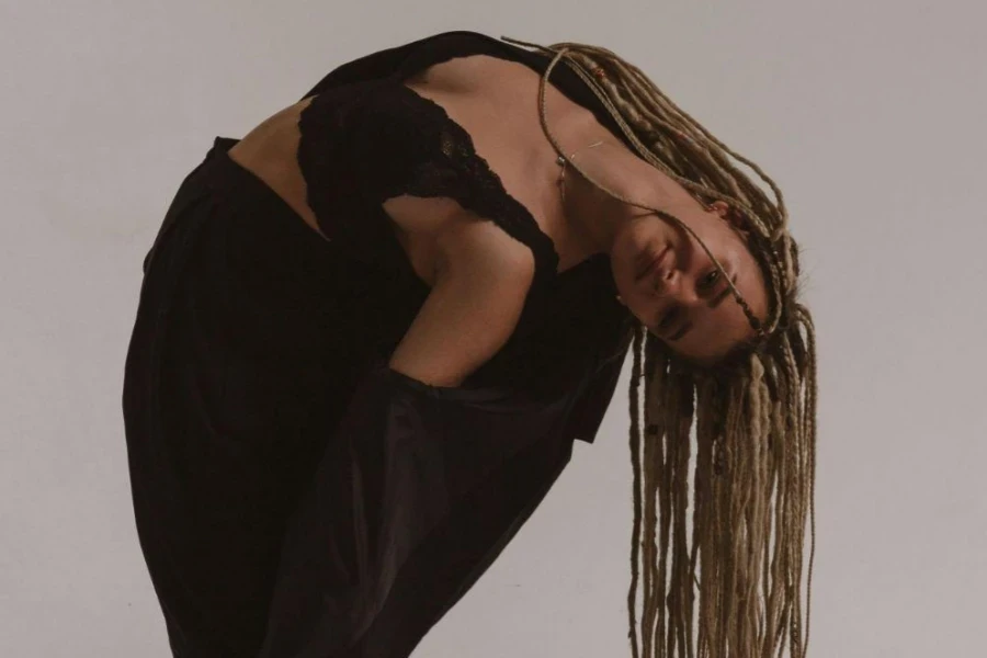 A Woman Wearing Lace Top and Black Blazer Bending Her Body while Posing at the Camera