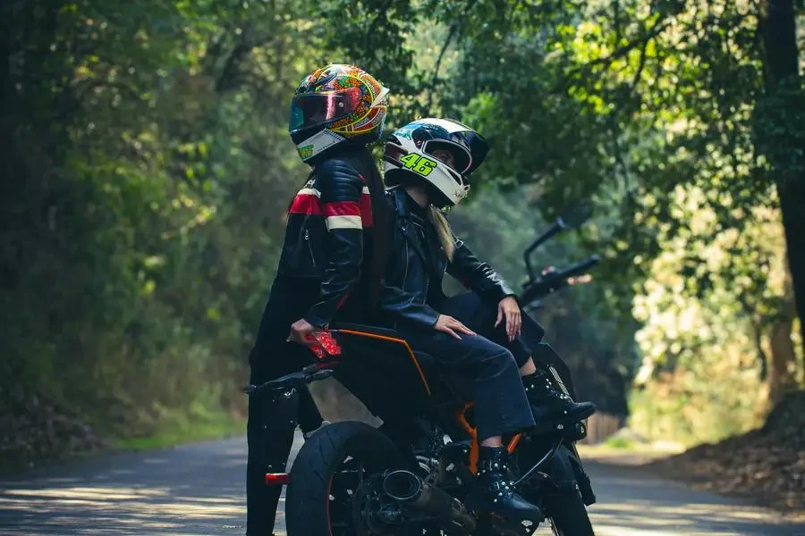 A couple riding on a motorcycle down a road by Jon