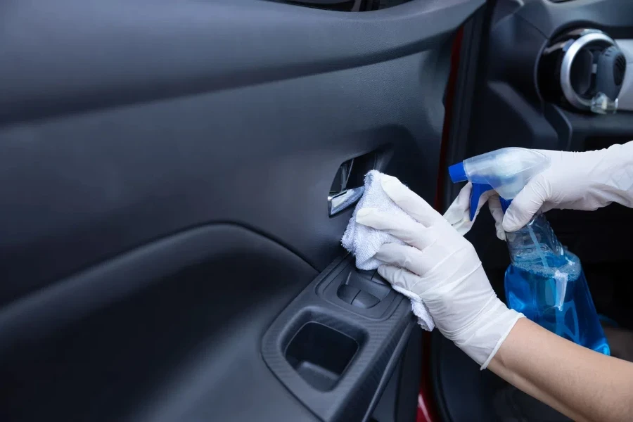 Un conductor desinfectando el interior del coche con spray y trapo