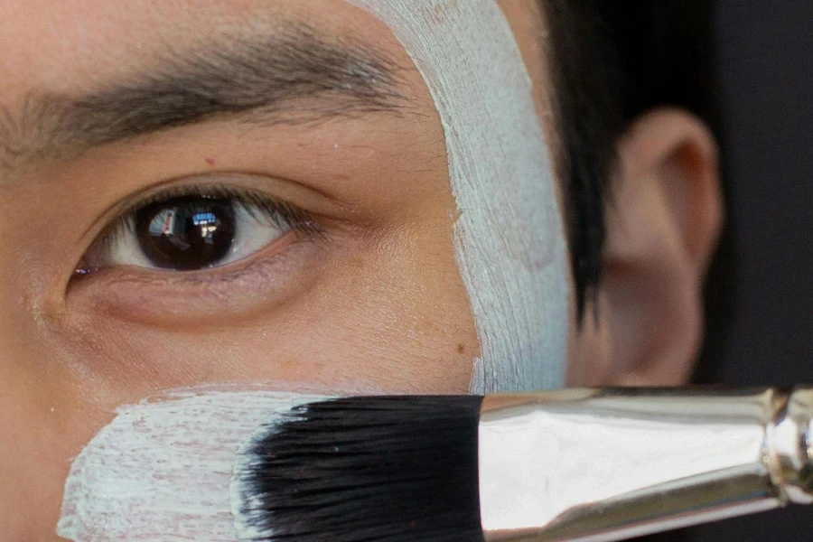 Anonymous Asian man applying clay mask