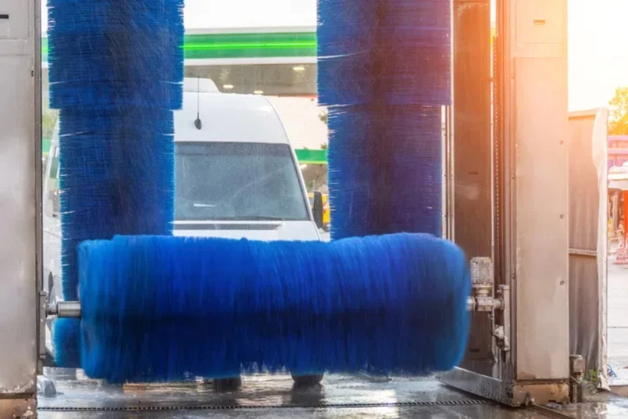 La brosse bleue de lavage automatique tourne en action, la mini-fourgonnette blanche sort prête à être propre