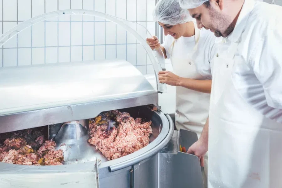 Butchers in butchery processing meat, man and woman